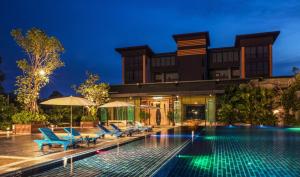 a hotel with a swimming pool at night at T Vintage in Bang Khla