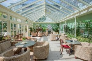 un giardino d'inverno vuoto con tavoli, sedie e una balconata di Rosleague Manor Hotel a Letterfrack