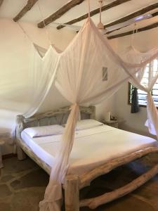 a bedroom with a canopy bed with mosquito netting at Bianca and Pietro House in Watamu