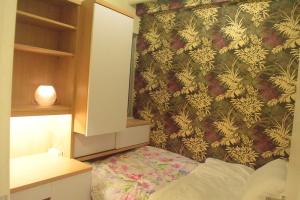 a bedroom with a wall with a floral wallpaper at Pakubuwono Terrace Apartment in Jakarta +5 photos