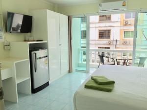 a kitchen with a bed with a tv and a refrigerator at Thai Orchid Guest House in Jomtien Beach