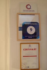 dois certificados emoldurados e um sinal numa parede em Hostel Humpolec em Humpolec