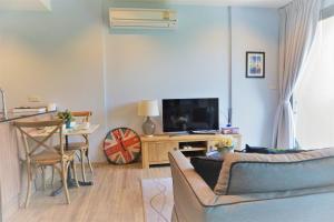 a living room with a couch and a table with a television at Rain Condo Hua Hin - Cha Am by SN in Cha Am