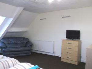 um quarto com um sofá e uma televisão numa cómoda em Durham house hotel em Gateshead