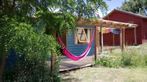 una casa azul con una hamaca en la terraza en Cabaña Acacia Mansa, en Villa Giardino