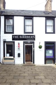 a white building with a sign that reads the barbers at Central Apartment Kelso in Kelso