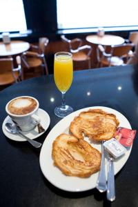 una mesa con un plato de comida y un vaso de zumo de naranja en Hostal Don Pedro, en Madrid