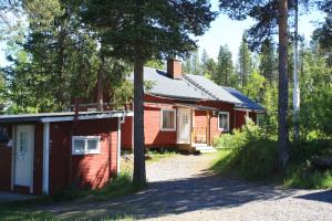 a red house in the woods with trees at Aurora Camp Kurravaara in Kurravaara