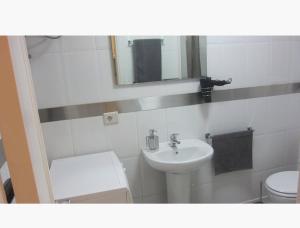 a bathroom with a sink and a toilet and a mirror at Apartamentos Syria Las Canteras in Las Palmas de Gran Canaria