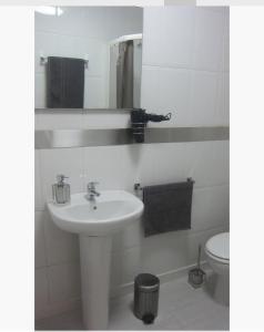 a white bathroom with a sink and a toilet at Apartamentos Syria Las Canteras in Las Palmas de Gran Canaria