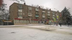 a large building on a street with snow on the ground at Уютная 1-квартира в центре города in Shakhty