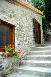 un edificio de piedra con escaleras y una puerta y flores en Arcogite en Vicdessos