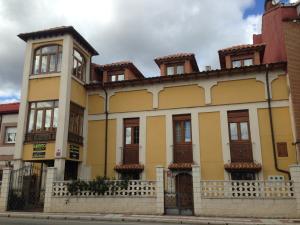 żółty budynek z oknami i ogrodzeniem w obiekcie Boleta A 5 minutos de León, casa con jardín w mieście San Andrés del Rabanedo