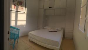 Le Club des Cigales في هييريس: غرفة نوم بيضاء صغيرة بها سرير وكرسي