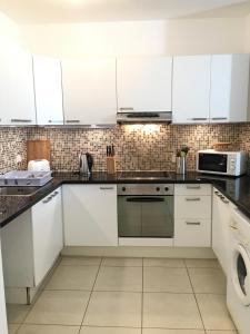a white kitchen with white cabinets and a dishwasher at Limnaria Westpark in Paphos