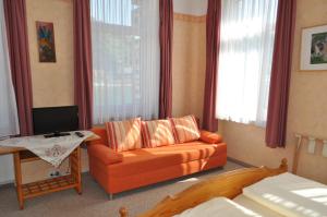 ein Wohnzimmer mit einem orangenen Sofa und einem TV in der Unterkunft Hotel am Markt Sankt Goar in Sankt Goar