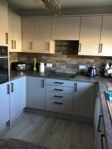 cocina con armarios blancos y suelo de madera en Christiesholidayhomes en Aviemore