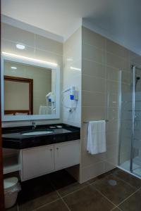 a bathroom with a sink and a shower and a mirror at Hotel Costa Linda in Porto da Cruz
