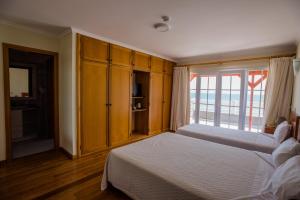 a bedroom with two beds and a large window at Hotel Costa Linda in Porto da Cruz
