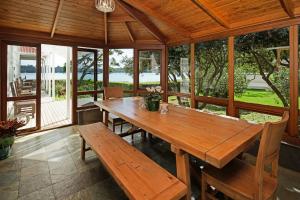 comedor con mesa de madera y bancos en Oakura Bay Villa, en Te Whau Bay