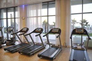 a group of treadmills in a gym with windows at West Tel Aviv- All Suites Hotel By The Sea in Tel Aviv