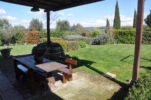a picnic table and a bench under a gazebo at Stalla Lunga in Magliano in Toscana