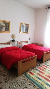 two beds in a bedroom with red sheets and a rug at Ristorante Albergo Roma in Legnano