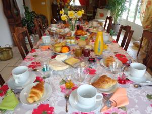 a table with croissants and cups and plates of food at B&B Les Cistelles in Saint-Nicolas-lès-Cîteaux