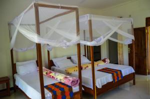 1 Schlafzimmer mit 2 Etagenbetten mit weißen Vorhängen in der Unterkunft Voyage Village in Mikumi