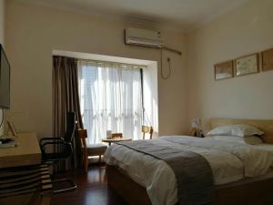 1 dormitorio con cama, escritorio y ventana en Xizhengjia Apartment Hotel Pazhou Complex, en Guangzhou