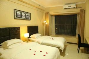 Dos camas en una habitación de hotel con rosas en las sábanas en Xizhengjia Apartment Hotel Pazhou Complex, en Guangzhou