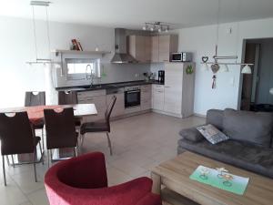 Haus am Leuchtfeuer في بيناموندا: غرفة معيشة ومطبخ مع أريكة وطاولة