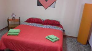 una camera da letto con un letto rosso e asciugamani verdi di Affittacamere di Fabio Principale a Talsano
