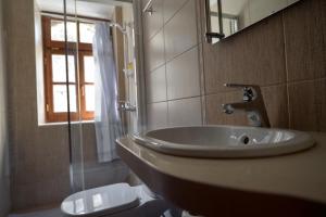 a bathroom with a sink and a toilet and a window at Hotel Kalemi 2 in Gjirokastër