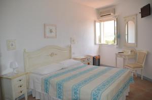 a bedroom with a bed and a window and a chair at Hotel Il Timone in Cugnana