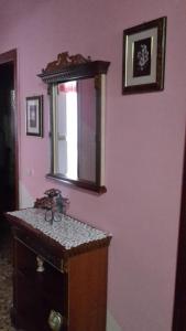 uno specchio su una parete rosa con cassettiera in legno di Affittacamere di Fabio Principale a Talsano