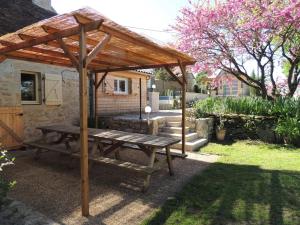 een picknicktafel onder een houten paviljoen in een tuin bij Le Pigeonnier in Martel