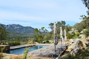 a resort pool with umbrellas and chairs and mountains at Les Petites Maisons in Sotta