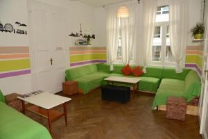 un salon avec un canapé vert et des tables dans l'établissement Budapest Party Hostel at Udvarom, à Budapest