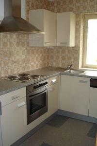 eine Küche mit weißen Schränken und einem Herd mit Backofen in der Unterkunft Landhaus Christophorus in Mallnitz