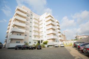 ein großes weißes Gebäude mit Autos auf einem Parkplatz in der Unterkunft Accra Luxury Apartments in Accra