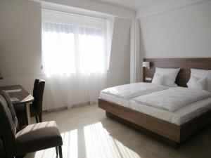 a bedroom with a bed and a desk and a window at Hotel & Mühlenapartments in Gernsbach