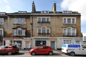 dois carros estacionados num parque de estacionamento em frente a um edifício em Luxury Regency Apartment in Bath City Centre em Bath