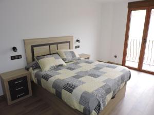 El Tranco Apartamentos في Villel: غرفة نوم مع سرير وبطانية مقلية