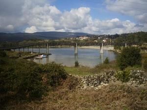 a bridge over a river with a boat in the water at Casa Torrre in Rianjo