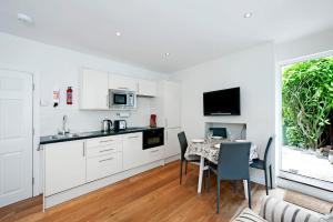 eine Küche mit weißen Schränken und einem Tisch mit Stühlen in der Unterkunft The Apartment, 24 West End Terrace, Winchester in Winchester