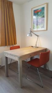 a wooden desk with a lamp and two chairs at Quiet spacious room in Amsterdam