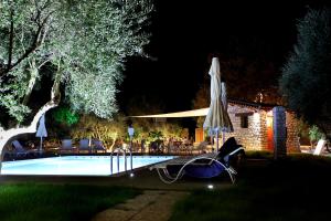 a swimming pool at night with an umbrella and chairs at Asfendamos in Zakharo