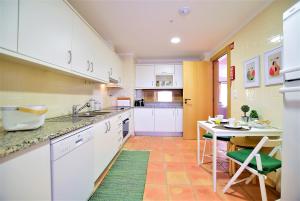 クアルテイラにあるT3 Vila Sol Villageの白いキャビネットとテーブルと椅子のあるキッチン