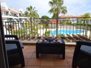 クアルテイラにあるT3 Vila Sol Villageの果物が置かれたテーブルとプールのあるバルコニー